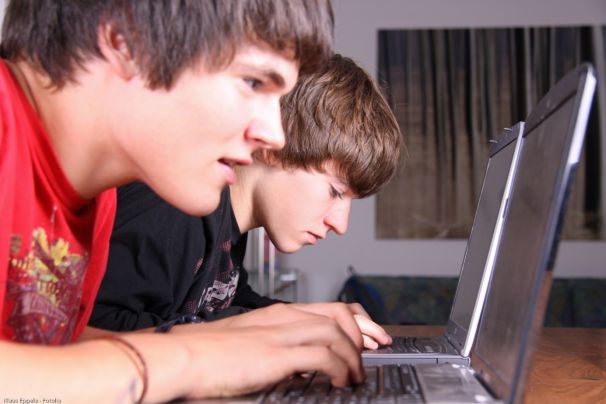 Zwei Jungen sehen konzentriert auf ihre Laptops.
